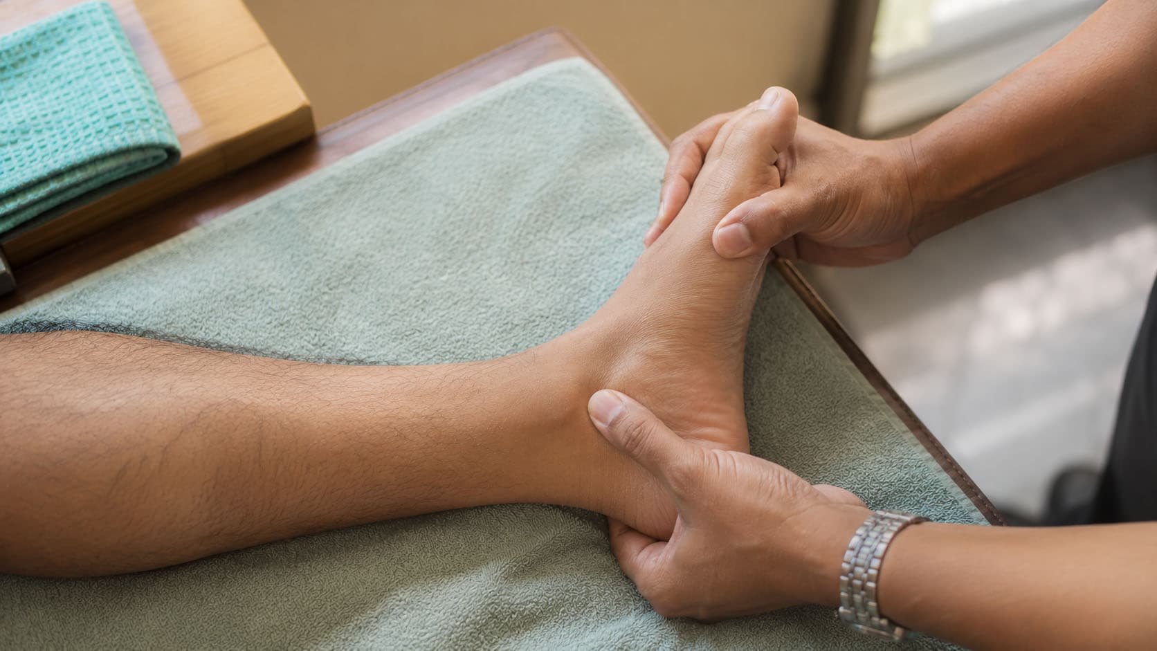 A podiatrist performing manual therapy on a patient's foot and ankle